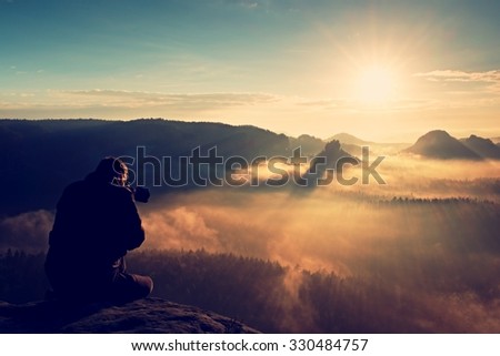 Photographer silhouette above a clouds sea, misty mountains
