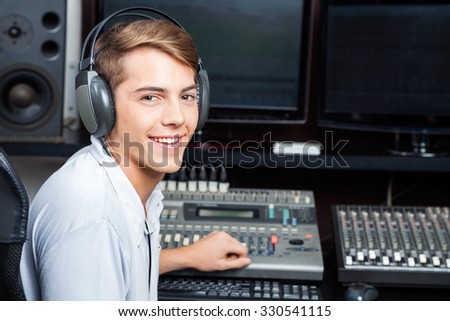 Side view portrait of handsome man mixing audio in recording studio