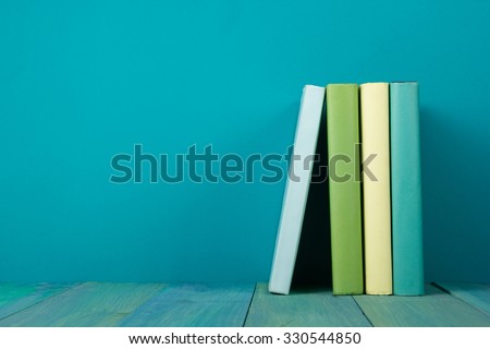 Row of books, grungy blue background, free copy space Vintage old hardback books on wooden shelf on the deck table, no labels, blank spine. Back to school. Education background