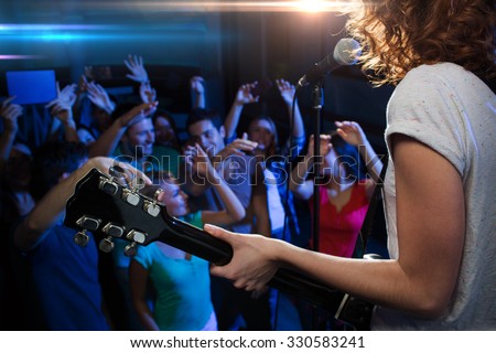 holidays, music, nightlife and people concept - close up of singer playing electric guitar and singing on stage over happy fans crowd waving hands at concert in night club Royalty-Free Stock Photo #330583241