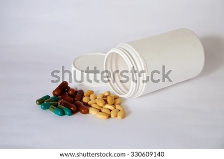 Group of different pills and white bottle multivitamins on a dark background
