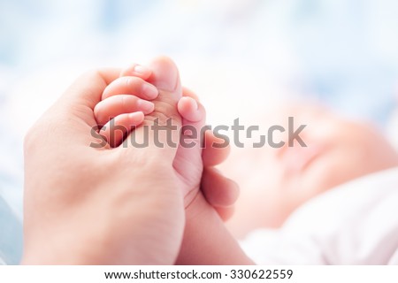 Holding Hands. hand the sleeping baby in the hand of parent close-up Royalty-Free Stock Photo #330622559