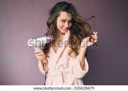  Close up portrait of beautiful young woman in pink bathrobe  drying hairstyle. Cute young  lady smiling . Royalty-Free Stock Photo #330628679
