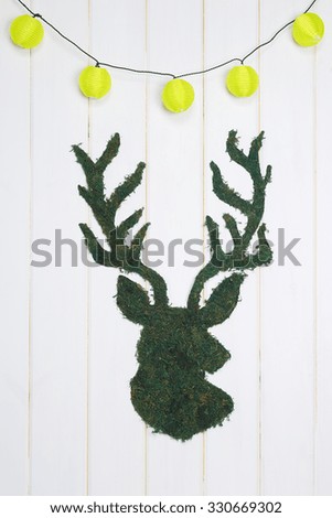 Silhouette of a deer on a white wooden background with a garland