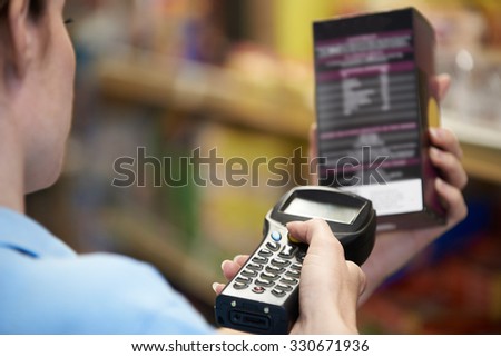 Sales Assistant Checking Stock Levels In Supermarket Using Hand Held Device