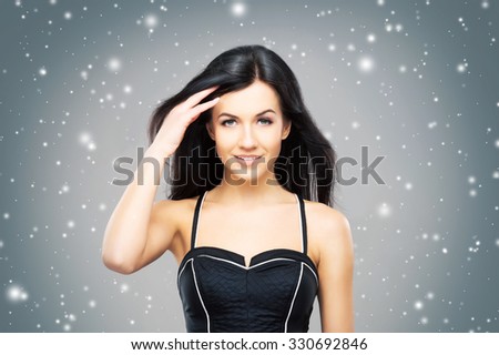 Portrait of the young, beautiful and cute girl with a blowing brunette hair over background with snowflakes.