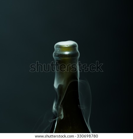 Closeup view of one new open full champagne wive sweet or dry drink green glass bottle with beautiful white smoke for celebration christmas or new year in studio on black background, square picture