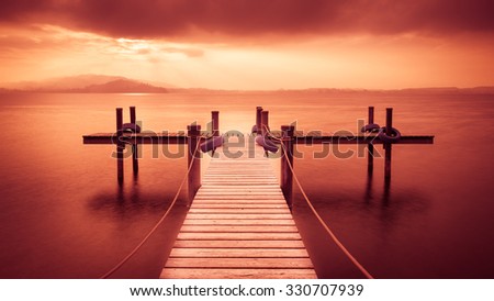 Wooden pier on the lake. Fog. Long exposure. Expression red