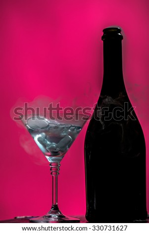 Closeup of glamour open full champagne wive sweet or dry drink green glass bottle and goblet with white smoke and ice for celebration christmas or new year on pink background, vertical picture