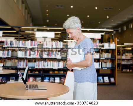 Elderly lady standing next to table with laptop