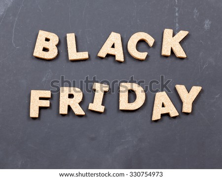 Black Friday sales image. Grunge background with cork textured letters. Letters are randomly arranged in a chaotic manner. Dark grey background is rough and damaged. Copy space below.