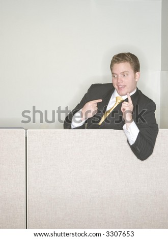 Businessman is taunting his coworkers from above at the top of his cubicle pointing his finger in the air in a sign of his success in the office