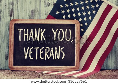 the text thank you veterans written in a chalkboard and a flag of the United States, on a rustic wooden background Royalty-Free Stock Photo #330827561