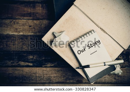 Our Story word on pages sketch book on wood table vertical  Royalty-Free Stock Photo #330828347