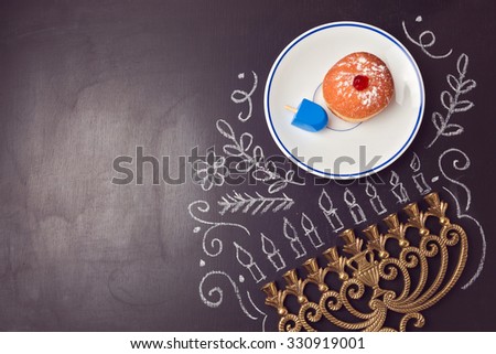 Hanukkah holiday background with menorah and sufganiyot over chalkboard. View from above