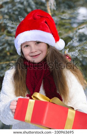 Adorable  girl holding Christmas baubles in hands in winter forest