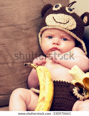 An infant of two months old is propped in a moneky costume with an 8x10 picture format.