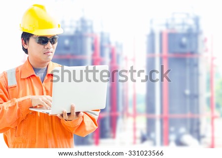 engineer with a notebook in an oilfield. Tank farm background