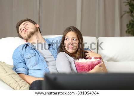 Couple incompatibility problems watching tv sitting on a couch at home Royalty-Free Stock Photo #331054964