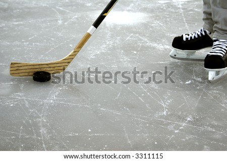 a hockey stick and puck and ice skates on the ice