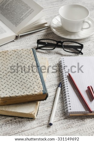 A stack of books, notebook and glasses , coffee cup on white wooden table. The concept of education and training