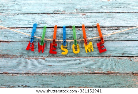 word awesome fasten clothespins on a rope behind a wooden background