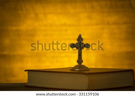 The cross is located on the Bible, against a backdrop of dark wood.
