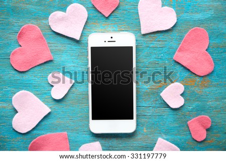 Smart phone with blank screen and hearts on old wooden table Royalty-Free Stock Photo #331197779