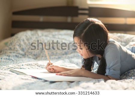 Beautiful asian girl writing to diary on the bed Royalty-Free Stock Photo #331214633