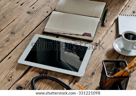 Tablet computer with a notebook and a cup of black coffee in the workplace. Top view. Copy space. Free space for text
