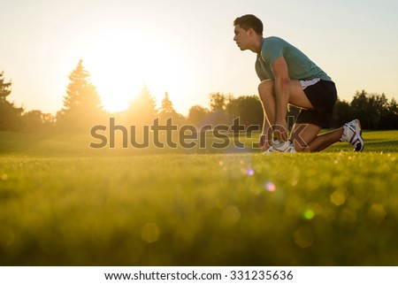 Running athlete is ready to start. Sportsman at the start. Evening jogging. Athletics. Scamper on the nature. Royalty-Free Stock Photo #331235636
