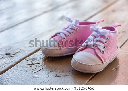 Pink baby girl shoes on a wooden floor outdoors