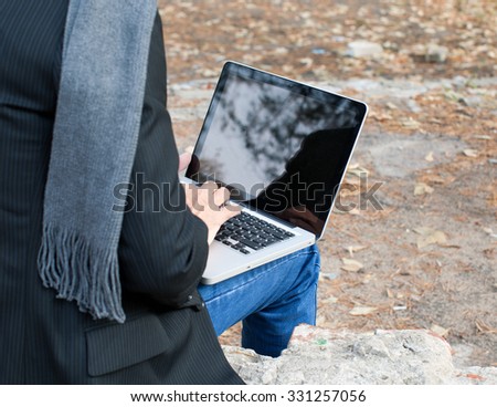 Laptop and mans hands sitting outside.
