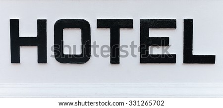 The word HOTEL in bold, black, hand painted, capital letters on a white background, part of a hotel's name sign.