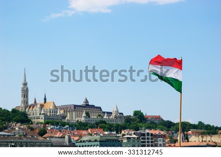 Flag of the Republic of Hungary waving in the wind. On the background is the historic district of Buda, the old part of Budapest. Selective focus.