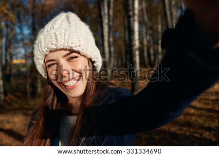 Technology internet and happiness concept. Woman content girl taking self picture selfie with smartphone camera while walking outdoors in autumn park