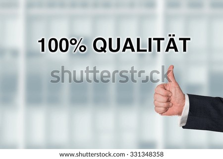 Business man pointing at the words 100% quality, with an office facade background