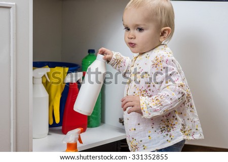 Toddler playing with household cleaners at home Royalty-Free Stock Photo #331352855