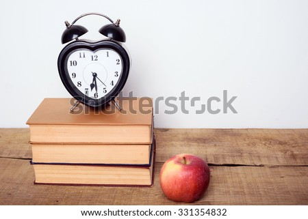 books, alarm clock, notepad and apple on wooden background. Education equipment, education concept