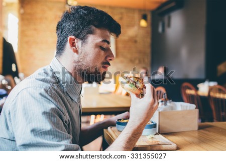 Man is eating in a restaurant and enjoying delicious food  Royalty-Free Stock Photo #331355027