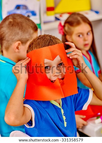 Group kids holding colored paper on table in kindergarten .