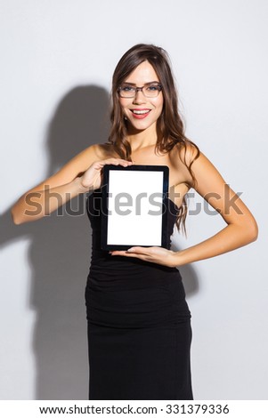 stylish girl in a black business dress and sunglasses standing on a white background with a snow-white smile, smiling, picture with depth of field, selective focus on the tablet, instagram filter
