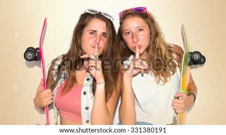Two friends with their skateboards making silence gesture