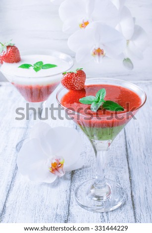 Fresh fruit and berry cocktail with strawberries, kiwi, banana and mint leaf on Ã?Â background the shabby wooden boards and white orchid