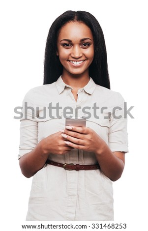 Beauty with smart phone. Beautiful young African woman holding mobile phone and smiling while standing against white background