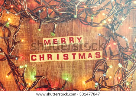Christmas concept with wooden blocks and christmas lights on a wooden table