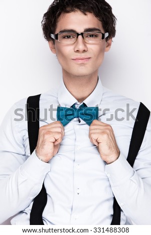 Handsome cheerful young man wearing glasses, a shirt with suspenders and a butterfly on his neck. Emotional people. Picture taken in the studio on a white background.