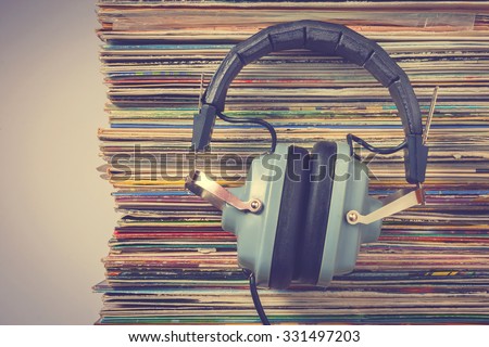 Audiophile headphones and a stack of old vinyl records.Stylized old color photo. Royalty-Free Stock Photo #331497203