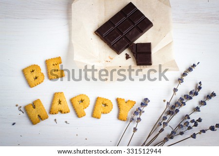Quote BE HAPPY. Still life image with biscuits, organic chocolate and vintage cup of green tea white wooden background. Top view collage made of biscuits. Retro toned and instagram filtered image. Royalty-Free Stock Photo #331512944