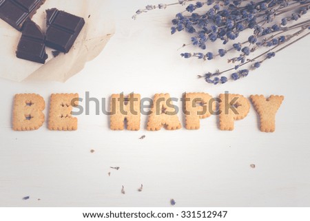 Quote BE HAPPY. Still life image with biscuits, organic chocolate and vintage cup of green tea white wooden background. Top view collage made of biscuits. Retro toned and instagram filtered image.
